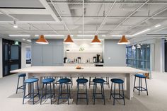 a large kitchen with blue stools and white counter tops in an office building or conference room