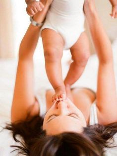 a woman laying on top of a bed next to a baby in a diaper