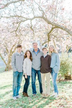 a family posing for a photo under the blossoming trees