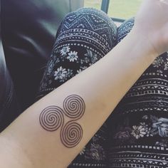 a woman's arm with a tattoo on it that has three spirals in the middle