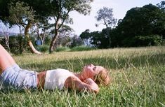 a woman laying in the grass with her eyes closed