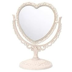 a white heart shaped mirror sitting on top of a stand