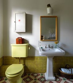 a yellow toilet sitting next to a white sink in a bathroom under a mirror on the wall