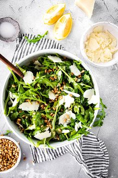 a salad with spinach, parmesan cheese and pine nuts in a bowl