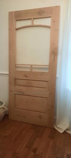 a wooden door in the corner of a room with wood flooring and white walls