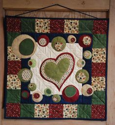 a quilted wall hanging with a heart on it