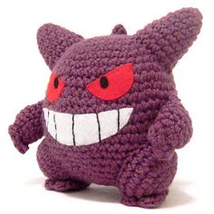 a crocheted stuffed animal with red eyes and fangs on it's face