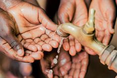 several people are washing their hands under a faucet with water coming out of it