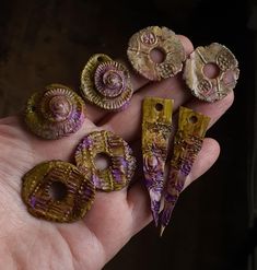 a person is holding five small pieces of jewelry