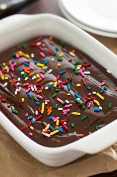 a chocolate cake with sprinkles in a white dish