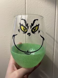 a person holding up a wine glass with an angry grin face painted on the side