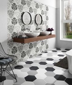 a bathroom with black and white tiles on the floor, two mirrors above the sink