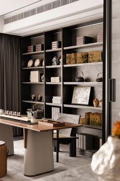 a room that has some bookshelves and chairs in it with vases on the table