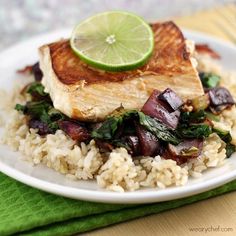 a white plate topped with rice covered in meat and veggies next to a lime wedge