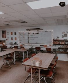 an empty classroom with many desks and books on the tables in front of them