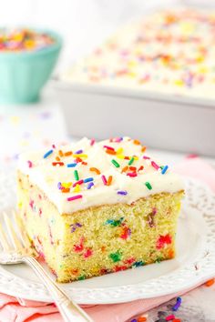 a slice of cake with white frosting and sprinkles on a plate