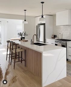 a kitchen with white cabinets and marble counter tops, an island in front of the sink