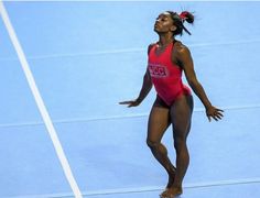 a woman in a red swimsuit standing on a tennis court with her arms outstretched