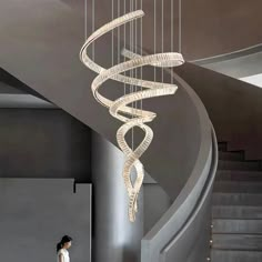 a woman standing in front of a spiral chandelier