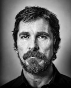 a black and white photo of a man with a goatee mustache looking at the camera