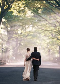 a man and woman are walking down the street together, dressed in formal attire with long sleeves