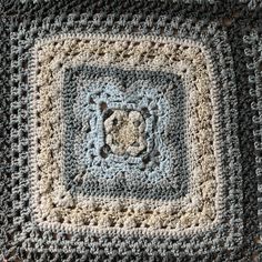 a crocheted granny blanket with a square in the center on top of it