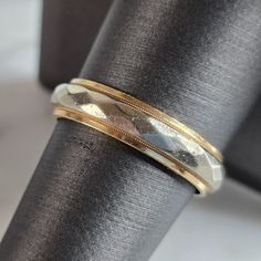 a gold and silver wedding band on top of a black piece of cloth with a white background