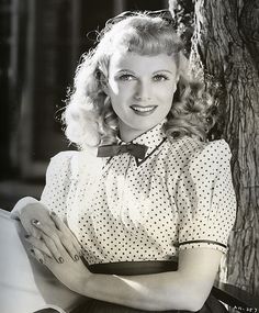 an old black and white photo of a woman sitting in front of a tree with her arms crossed