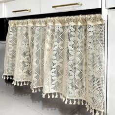 a kitchen curtain with tassels hanging from it's side in front of an oven