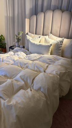 an unmade bed with white sheets and pillows