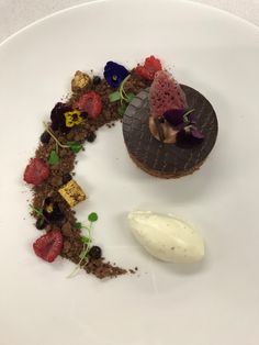 a white plate topped with a dessert covered in chocolate and strawberries next to a scoop of ice cream