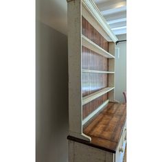 an empty bookcase in the corner of a room with white walls and wood flooring