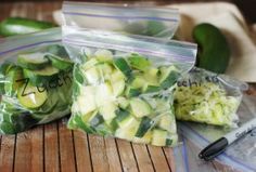 two bags of zucchini sitting on top of a wooden table next to an apple