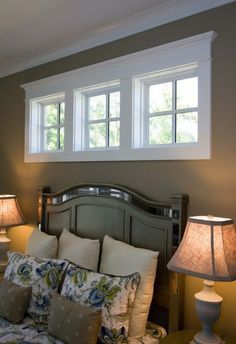 a bed with two lamps on either side of it and a window above the headboard