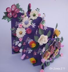 an assortment of paper flowers are displayed on a purple card with pink and yellow accents