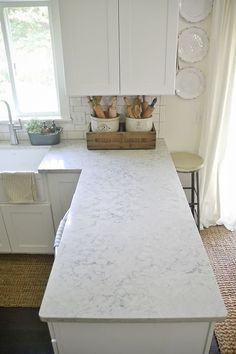 a white kitchen counter top sitting under a window