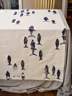 the table cloth has birds on it and is white with dark blue ink painted on it