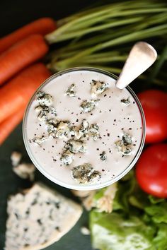 a glass filled with white liquid next to carrots and celery