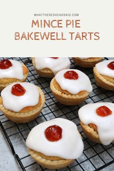 mini pies with white icing and strawberry jam are on a wire cooling rack