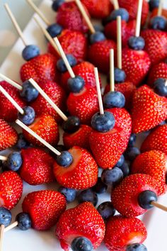 strawberries and blueberries are arranged on toothpicks