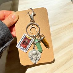 a person holding a keychain with charms attached to it