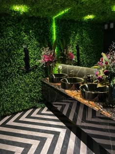 an indoor garden area with plants and potted plants on the wall, surrounded by black and white tiles