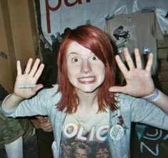 a girl with red hair is holding her hands up