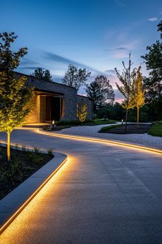 an outdoor walkway lit up at night with lights on the sides and trees in the background