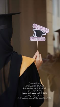 a person in a graduation gown holding up a sign