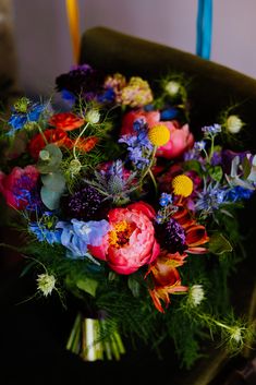 a bouquet of colorful flowers sitting on top of a green chair next to a candle