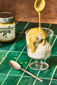 a spoon with some ice cream in it on a table next to a jar of mustard