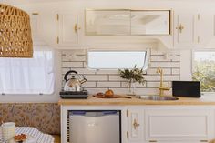 a small kitchen with white cabinets and gold trim on the counter top, along with a dishwasher