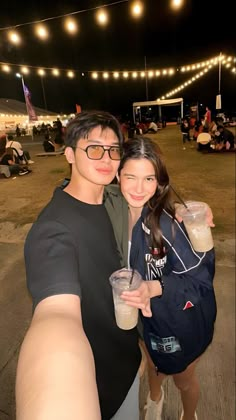 a man and woman taking a selfie in front of an outdoor venue at night