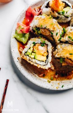 sushi is served on a white plate with chopsticks next to the dish